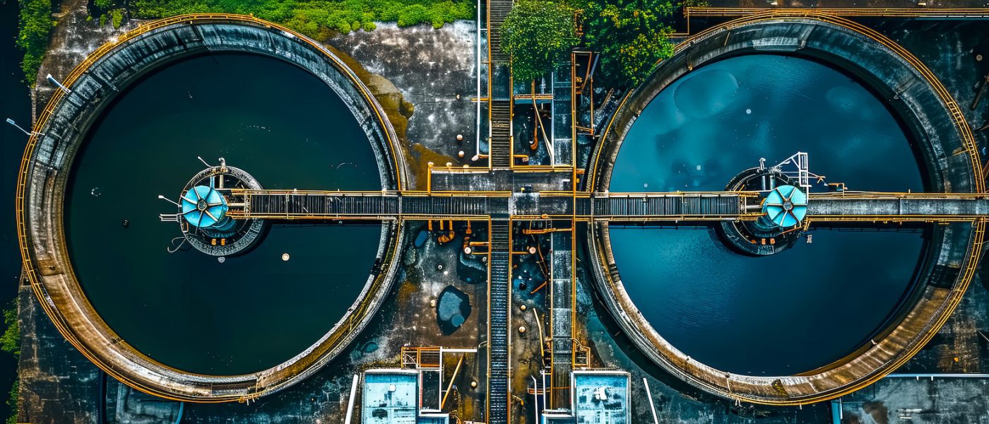 Aerial view of wastewater treatment plant with circular settling tanks and central pipework